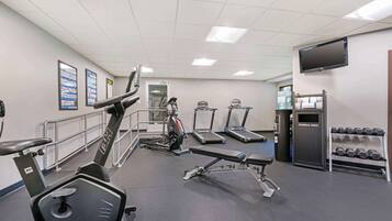 Et fitnesscenter med løbebånd, vægtbænke og håndvægte.