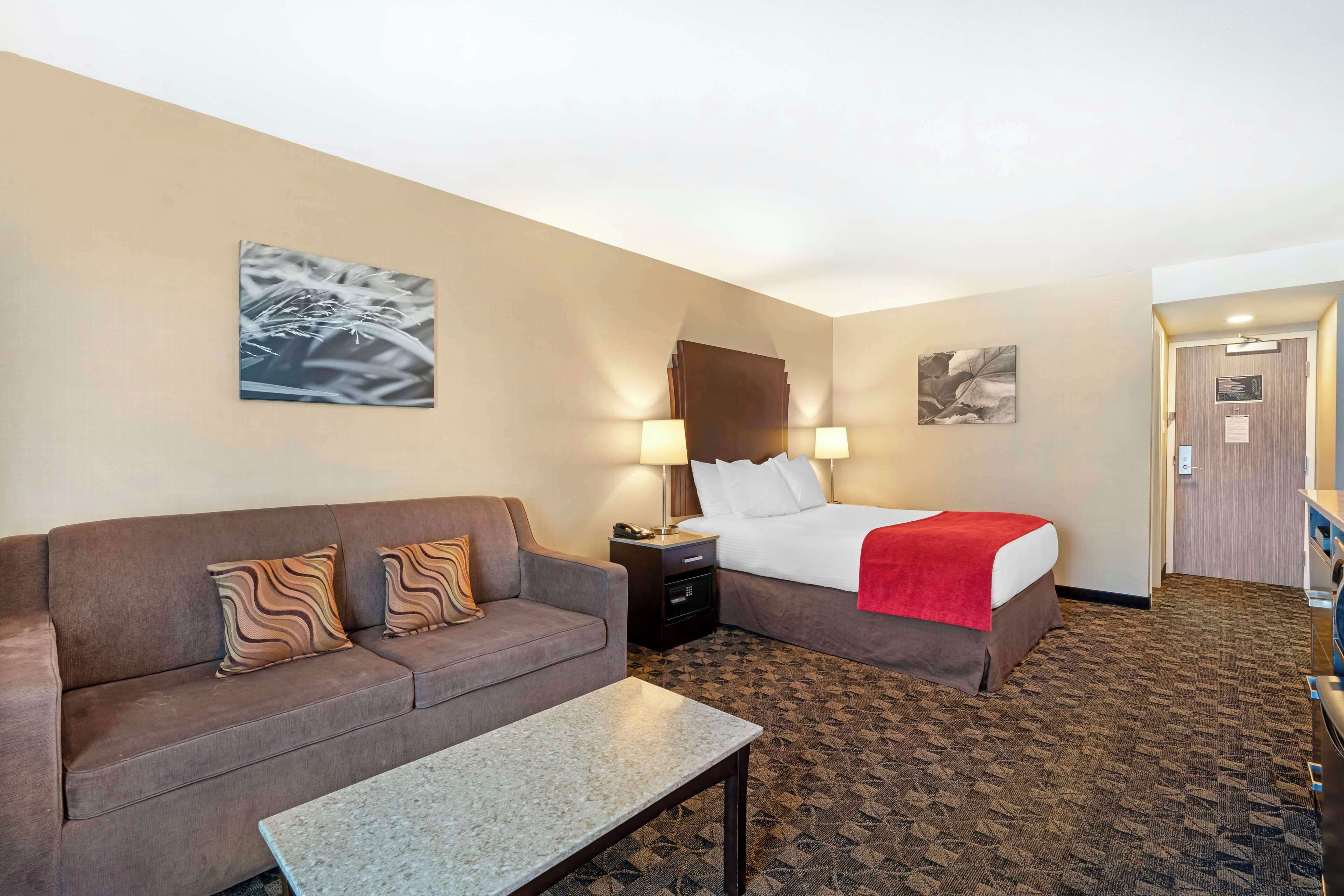 A hotel room with a sofa, a bed, a nightstand, and a table.