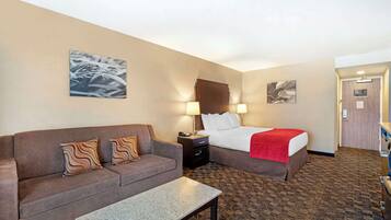A hotel room with a sofa, a bed, a nightstand, and a table.