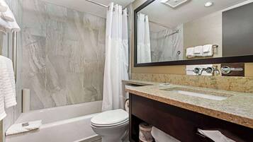 Une salle de bain moderne avec une baignoire, des toilettes et un grand miroir au-dessus du lavabo.
