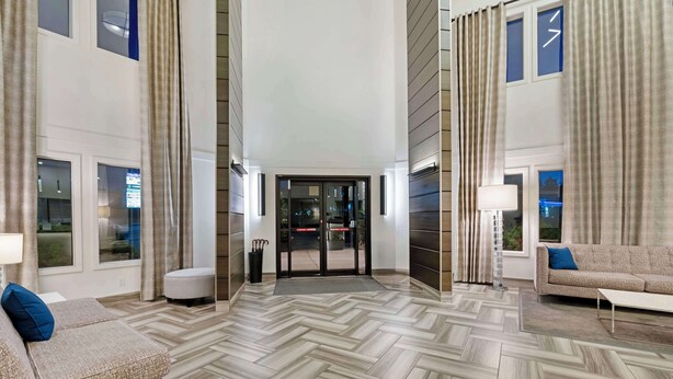 Un moderno vestíbulo de hotel con suelo de diseño en patrón espiga, un mostrador de recepción y un sofá con un cojín azul.