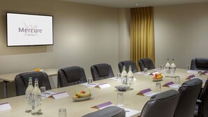 A conference room with a long table, chairs, name cards, water bottles, and a fruit bowl. - Mercure Hatfield Oak (Hatfield)
