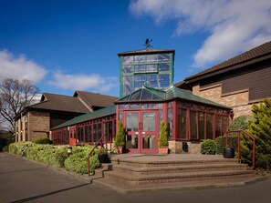 A building with a green-roofed conservatory, brick walls, and a clear blue sky. - Mercure Hatfield Oak (Hatfield)
