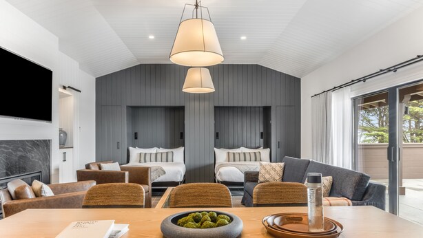 A modern living room with a large wooden table, two sofas, and a TV mounted on the wall. - The Lodge at Bodega Bay (Bodega Bay)