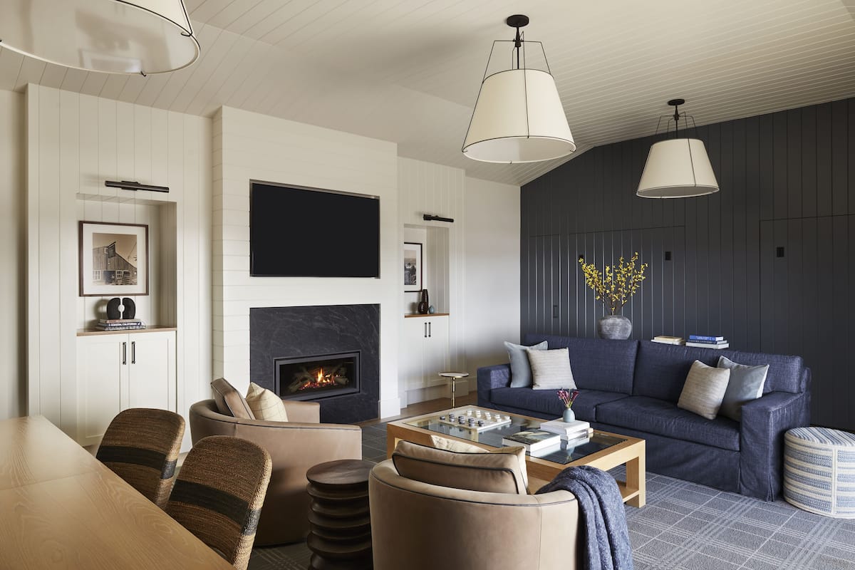 A modern living room with a fireplace, a sofa set, a coffee table, and a dining area with chairs.
