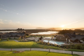 Zona residencial con piscina, casas y vista al cuerpo de agua al atardecer.
