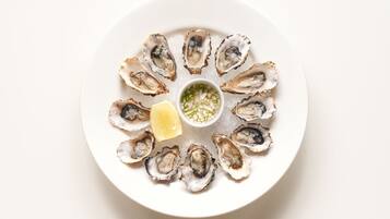 A plate of oysters with a lemon wedge and a small bowl of sauce.