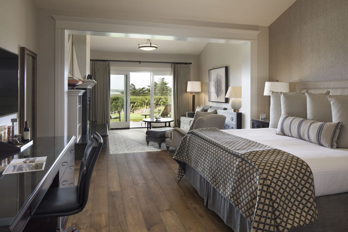 A hotel room with a bed, a desk, a chair, a television, and a view of the outdoors.