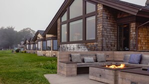 Un edificio moderno con ventanas amplias, fachada de piedra y terraza exterior con una chimenea.