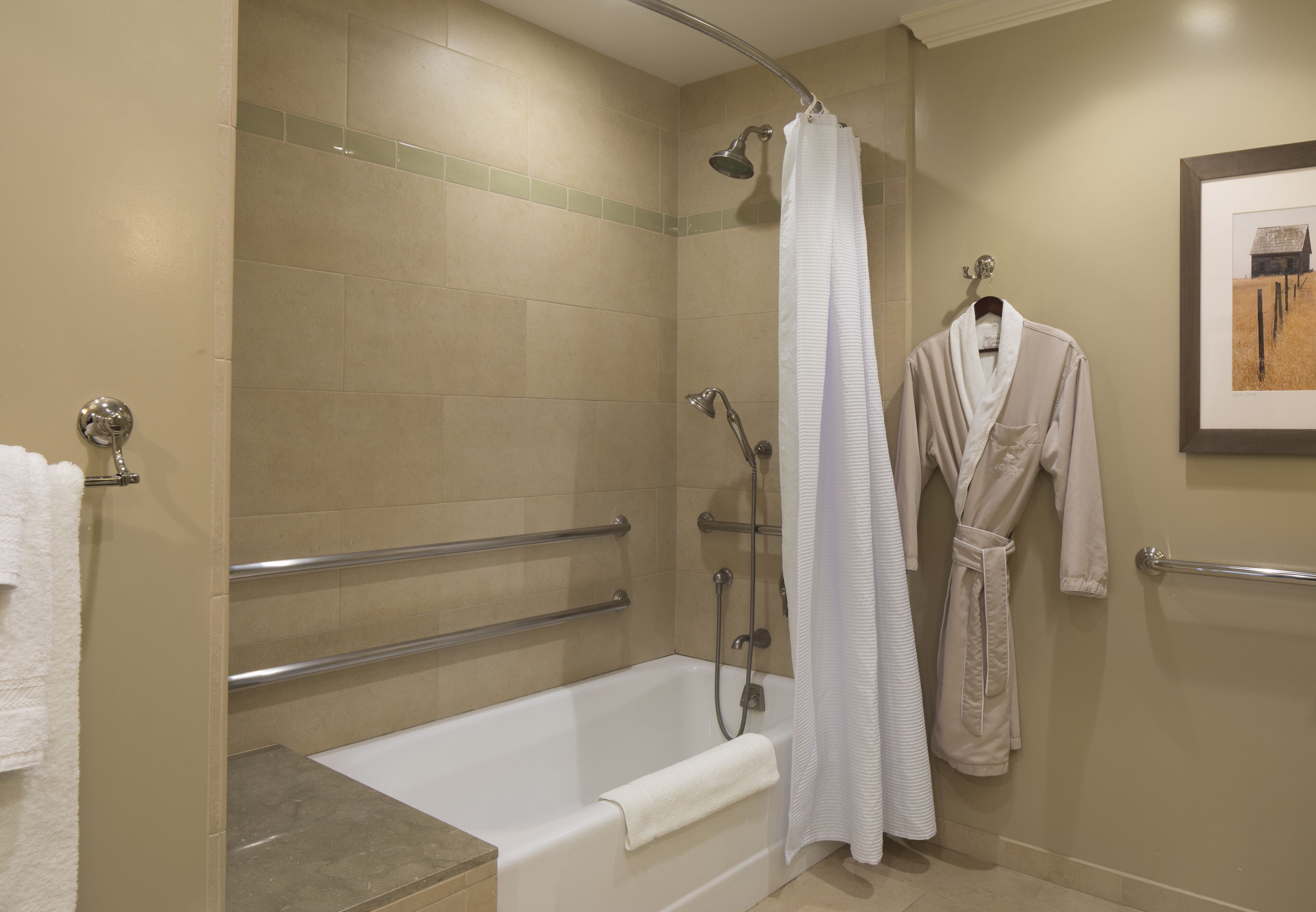 A bathroom with a bathtub, shower, and a robe hanging on the wall.