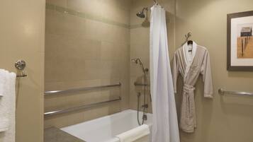 A bathroom with a bathtub, shower, and a robe hanging on the wall.