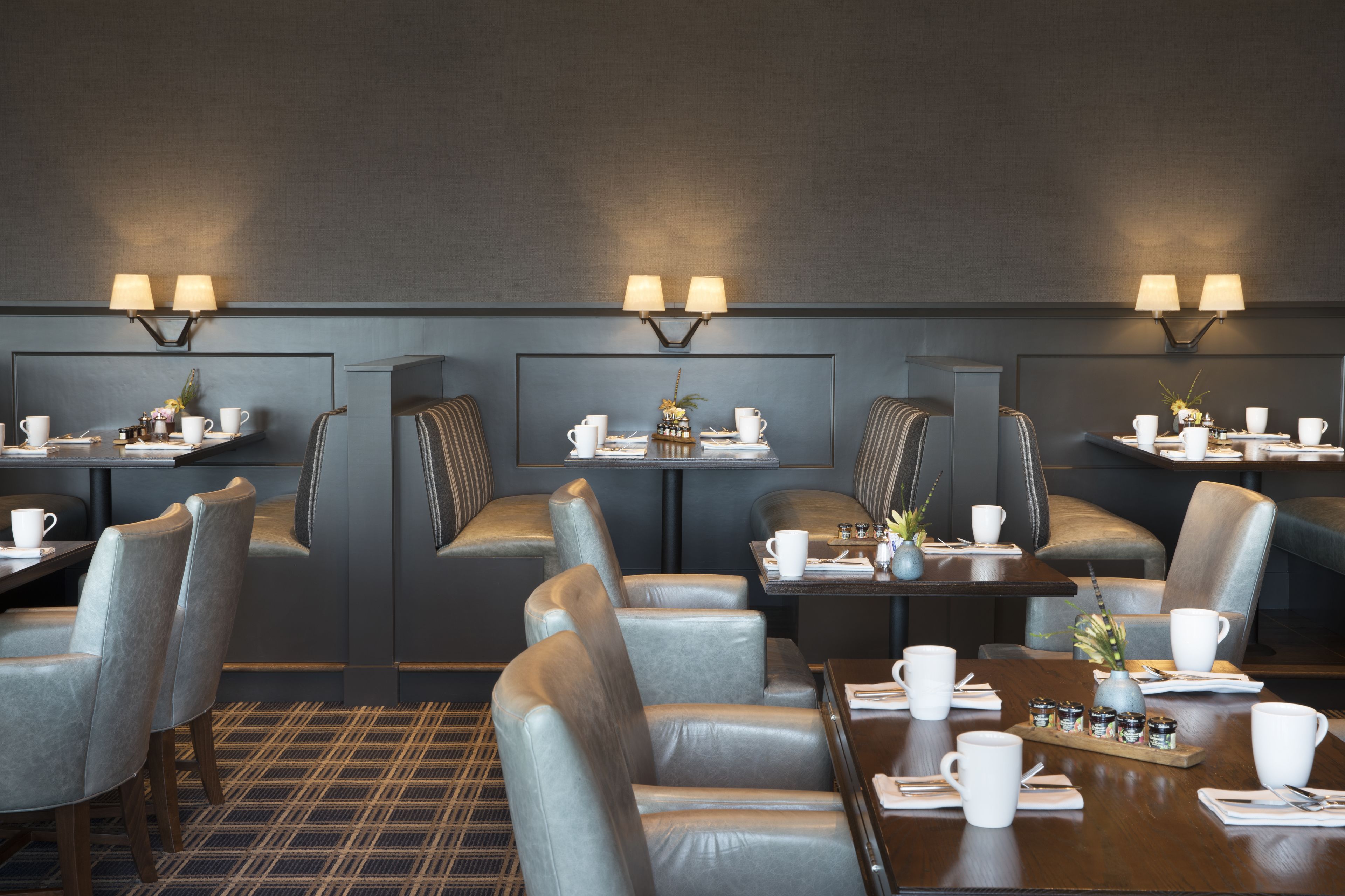 Een moderne eetruimte met zitbanken en tafels, voorzien van lampen en kleine planten.