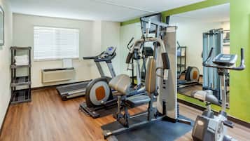 A gym with cardio machines, weight training equipment, and a mirrored wall.