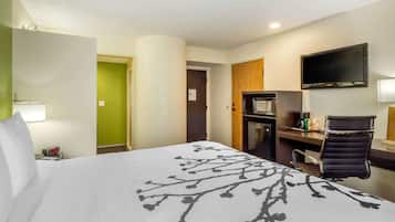 Habitación de hotel con cama, escritorio, silla, televisor y microondas.