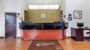 A reception desk with a 'Sleep Inn' sign, a welcome mat, a door, and a computer on a desk.