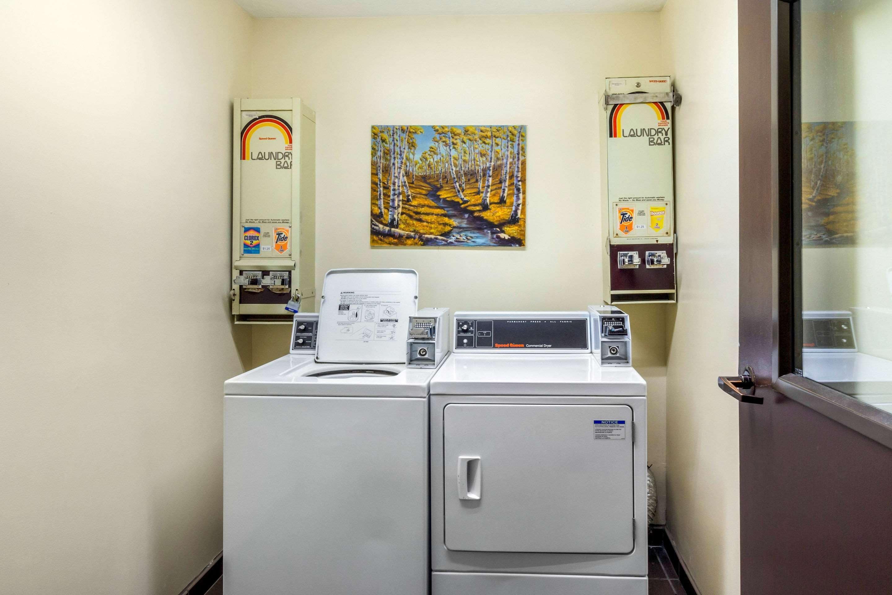 A laundry room with a washing machine, dryer, and two wall-mounted dryers.