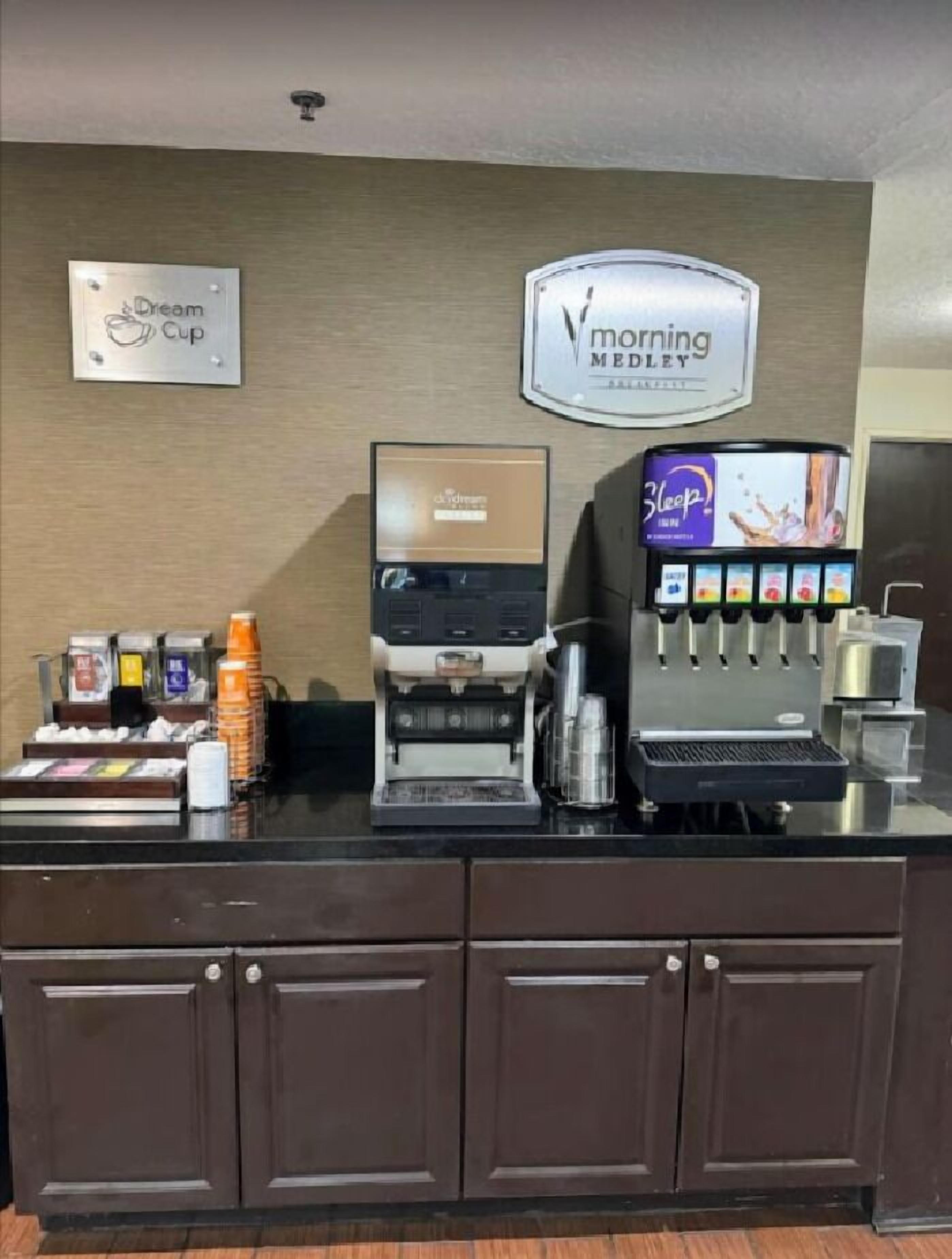 A coffee station with a coffee machine, a milk frother, and a selection of coffee pods.
