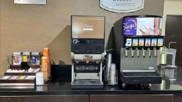 A coffee station with a coffee machine, a milk frother, and a selection of coffee pods.