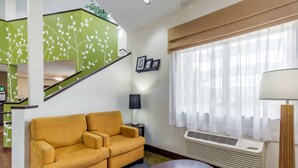 A living room with a sofa, a lamp, a radiator, and a window with curtains.
