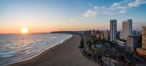 Un paysage urbain côtier avec une plage, des immeubles de grande hauteur et un ciel dégagé.