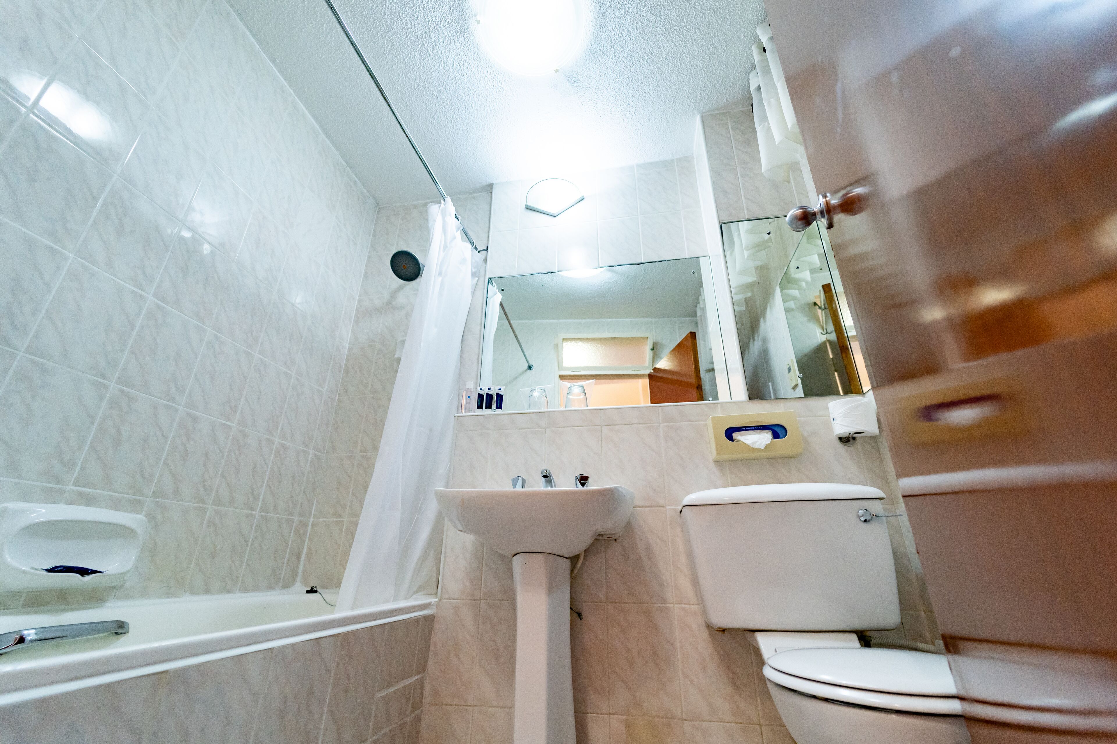 Un baño con bañera, lavamanos, inodoro y espejo.