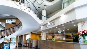 A reception area with a marble counter, a receptionist, and a staircase. - Gooderson Tropicana Hotel (Durban)