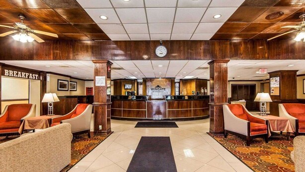 Um hall de hotel com uma recepção, um relógio e áreas de estar.