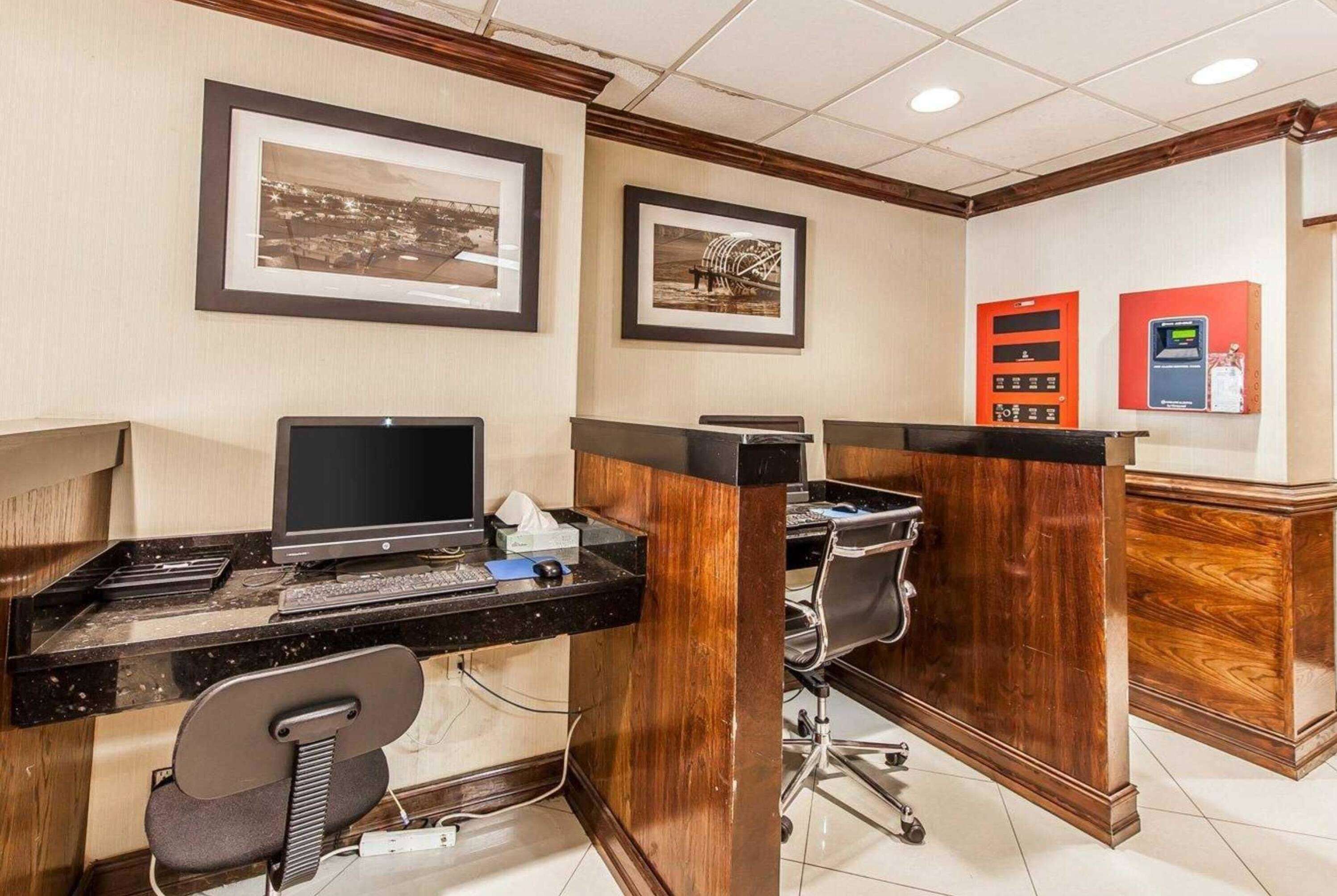 A hotel reception area with two computer workstations, a telephone, and a cash register.