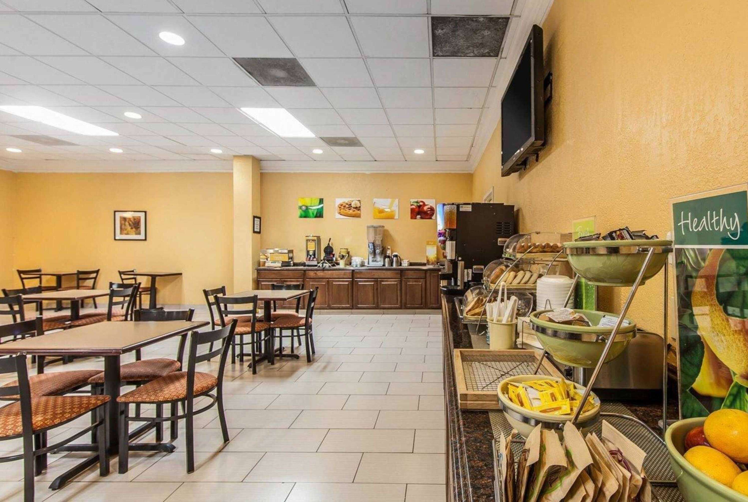 Eine Cafeteria mit Tischen, Stühlen, einer Küchenzeile und einer Theke mit Lebensmitteln.