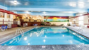 Piscina interna com um mural do pôr do sol, área de recepção com balcão e cadeiras, e escadaria que leva a um terraço.