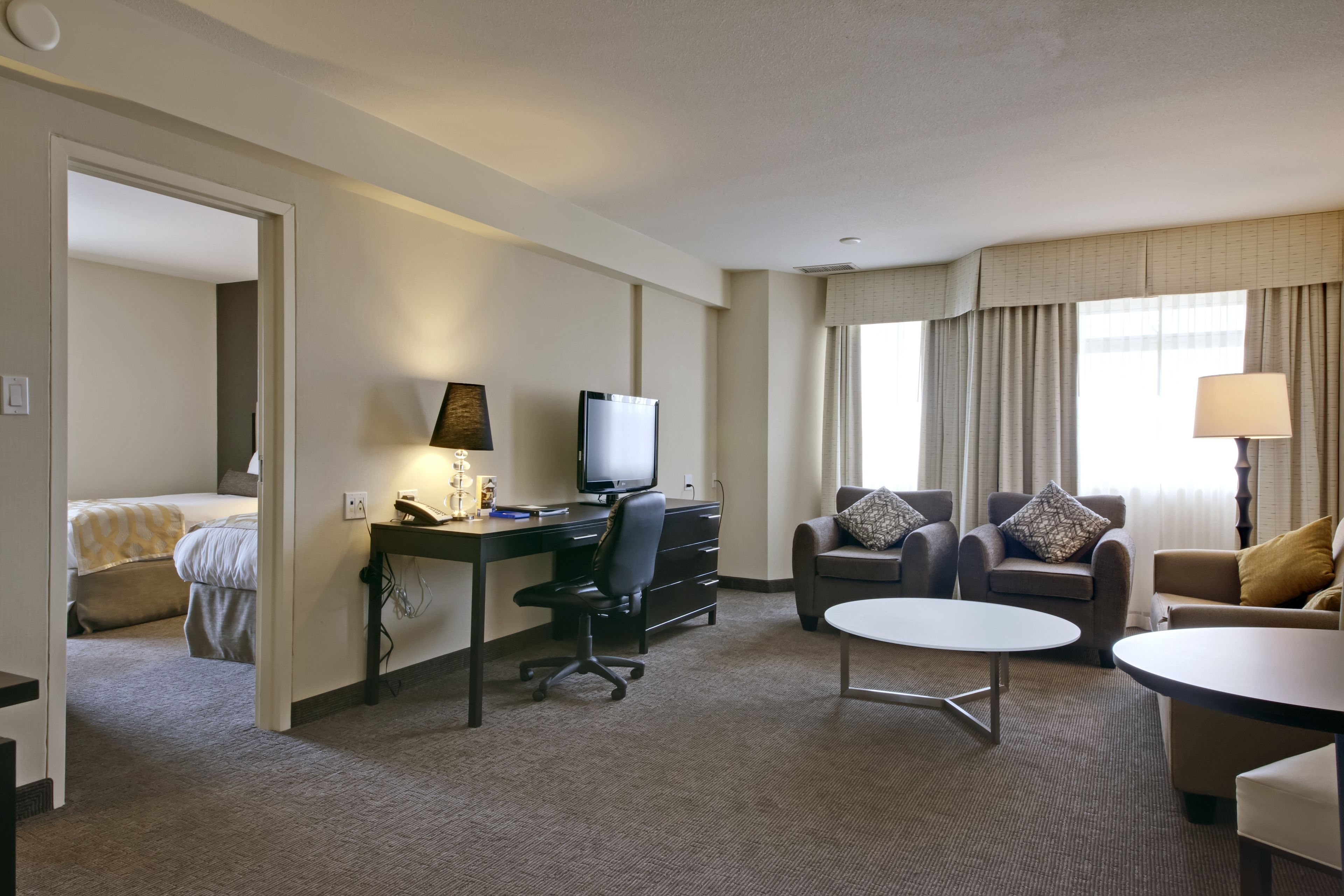 Een hotelkamer met een bed, een bureau met een computer, een stoel, een bank en een kleine tafel.