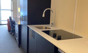A modern kitchen with a stainless steel sink, black cabinets, and a countertop.
