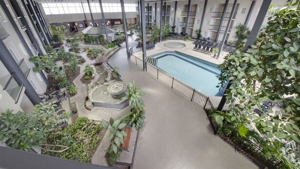 An indoor atrium with a central pool, surrounded by indoor plants and seating areas. - Coast Kamloops Hotel & Conference Centre (Kamloops)