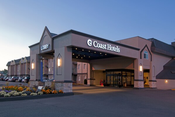 A hotel with a 'Lobby' sign, a covered entrance, and a parking lot.