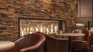 A restaurant with stone walls, leather chairs, and a fireplace. - Coast Kamloops Hotel & Conference Centre (Kamloops)