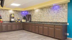 Una cocina moderna con protector de piedra, armarios color café y una cafetera integrada.