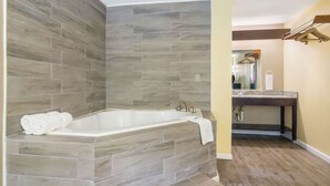 Un baño con una bañera independiente, un tocador con lavabo y un perchero para toallas.