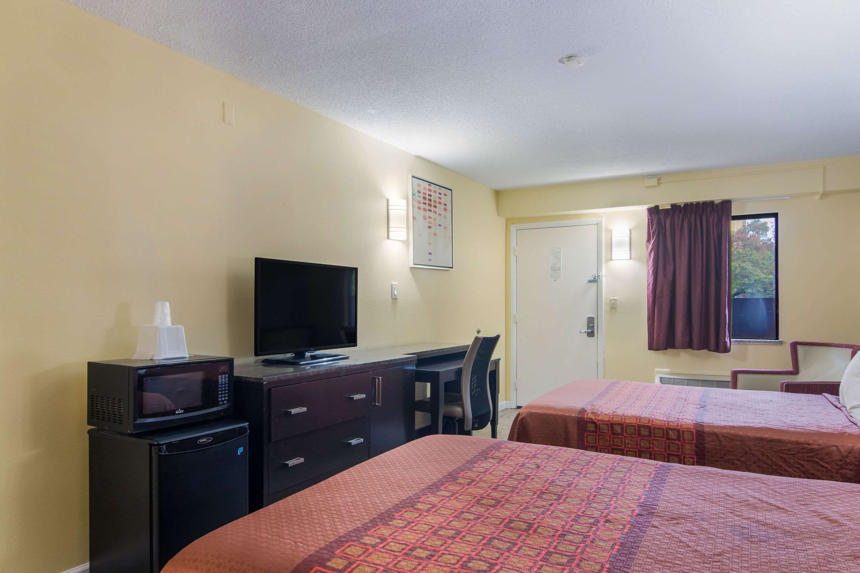 Una habitación de hotel con dos camas, un escritorio, televisión y microondas.
