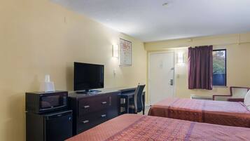 Una habitación de hotel con dos camas, un escritorio, televisión y microondas.