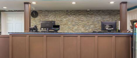 A reception area with a stone mosaic wall, two ATMs, and a clock.