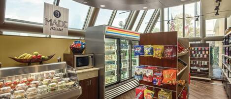 A food display area with a refrigerated section, a microwave, and a variety of packaged snacks.