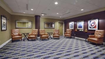 A spacious lobby with leather armchairs, a patterned carpet, and wall-mounted mirrors.