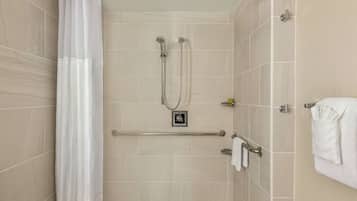 A shower with a glass door, a towel rack, and a handrail.