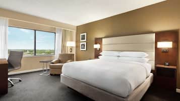 A hotel room with a large bed, a desk, a chair, and a view of the outdoors.