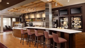 Un espace bar doté d’un long comptoir, de nombreux tabourets et d’étagères remplies de bouteilles.
