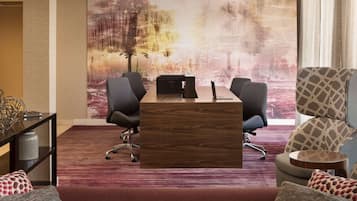 Una sala de conferencias con una mesa de madera, sillas de oficina negras y un cuadro abstracto grande en la pared.