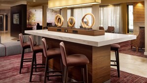 Un espace bar moderne doté d’un comptoir en marbre, d’éléments décoratifs en bois et d’un ensemble de miroirs circulaires originaux.