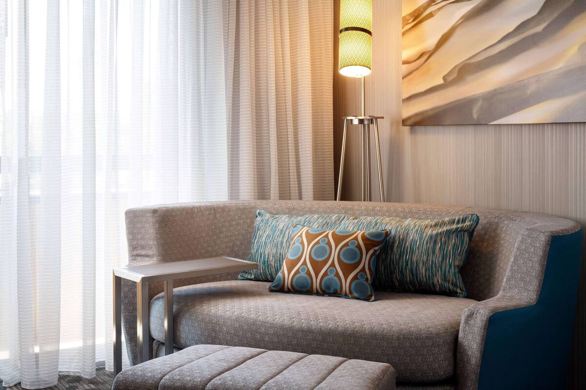 Un salon moderne avec un canapé, une table d’appoint et une lampe sur pied.