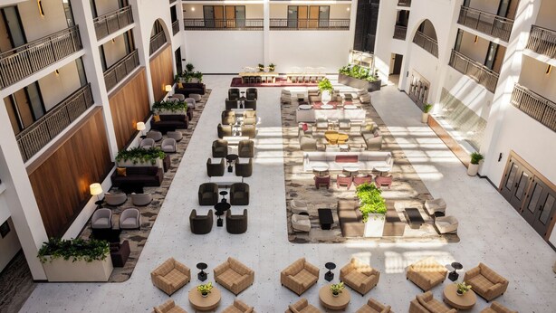 A spacious indoor courtyard with multiple seating areas, including sofas and chairs, arranged around a central table. - Embassy Suites by Hilton Cincinnati Northeast Blue Ash (Cincinnati)