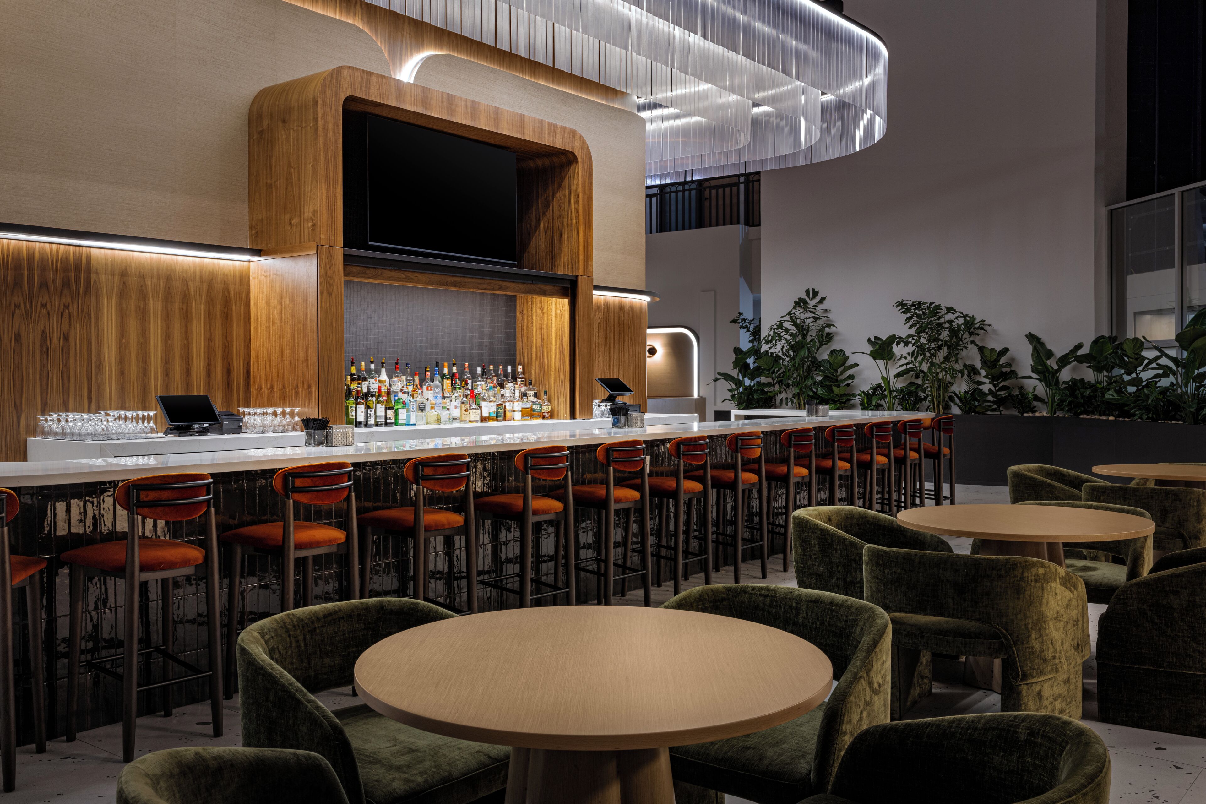 Un área de bar moderna con una barra larga, varios taburetes y una variedad de botellas.